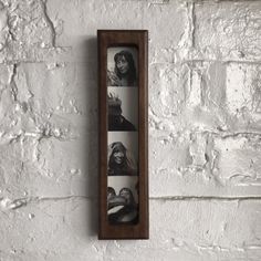 a wooden frame hanging on the side of a white brick wall with four photos in it