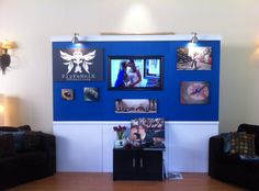 a living room with blue walls and pictures on the wall, two black couches