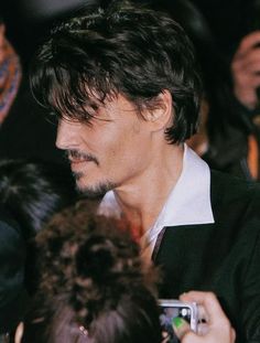 a man with dark hair and white shirt is surrounded by people