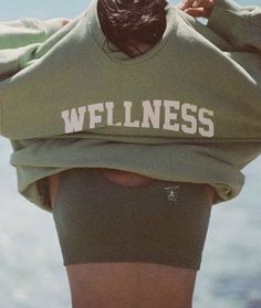 a woman with her back to the camera wearing a sweatshirt that says wfllness