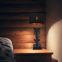 a skeleton lamp sitting on top of a wooden table next to a night stand with a light on it