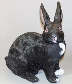 a black and white rabbit figurine sitting on top of a table next to a wall