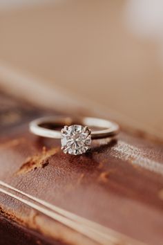 an engagement ring sitting on top of a book with a diamond in the middle,