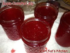 four jars filled with red liquid sitting on top of a table