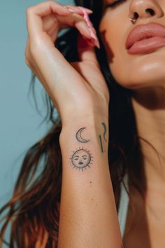 a woman with a sun and moon tattoo on her left arm holding a toothbrush