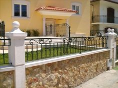 a house that has a fence in front of it and some bushes on the other side