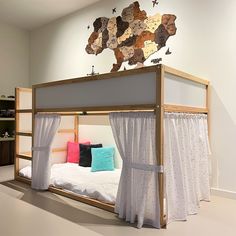 a bunk bed with curtains and pillows on it in a room that has white walls