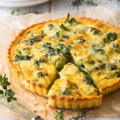 a quiche with broccoli and cheese is on a piece of parchment paper