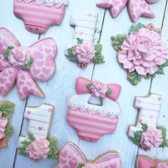 decorated cookies with pink and white designs are arranged on a wooden table next to each other