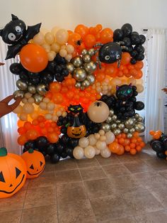 an assortment of halloween balloons and pumpkins on the floor in front of a wall