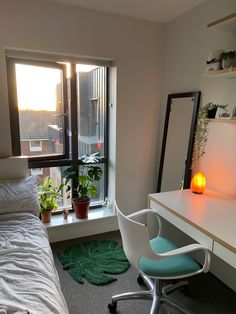 a bedroom with a bed, desk and chair next to a window that looks out onto the city