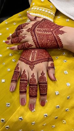 two hands with henna designs on them, one is holding the other's hand