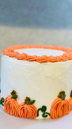 a white cake with orange frosting and pumpkin decorations