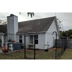 a white house with a black fence around it and a grill on the front yard