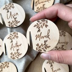 a person is holding some wooden magnets with names and leaves on them that spell out their name