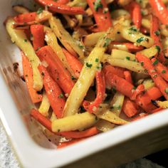 carrots and other vegetables are mixed together in a casserole dish with parsley on top