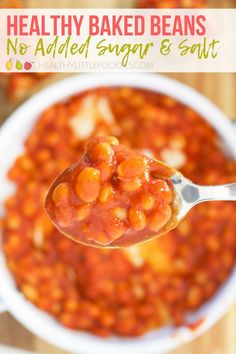 a spoon full of baked beans in a white bowl with text overlay that reads healthy baked beans no added sugar & salt