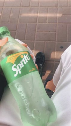 a bottle of sprite water sitting on someone's lap