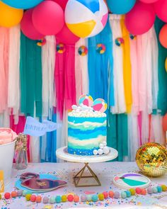 a table topped with a cake and balloons