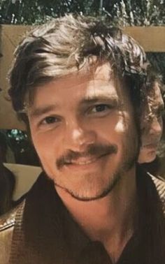 a close up of a person wearing a suit and tie with a smile on his face