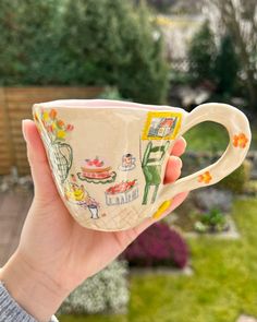 a hand holding a coffee cup with pictures on it