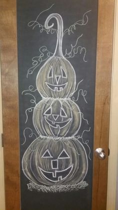 a chalkboard drawing of three pumpkins on a door