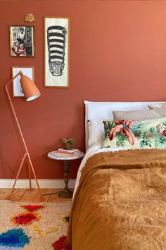 a bed room with a neatly made bed next to a lamp and pictures on the wall