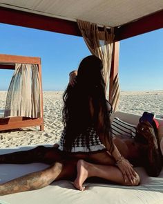 a woman sitting on top of a bed under a canopy