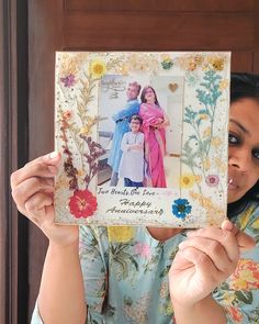 a woman holding up a photo frame with flowers on it