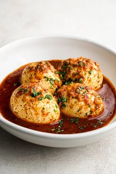 some food in a white bowl on top of a table with sauce and garnish