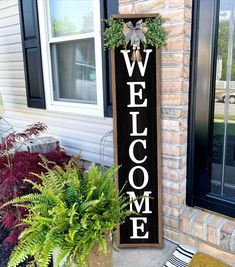 a welcome sign sitting in front of a house next to a planter filled with potted plants