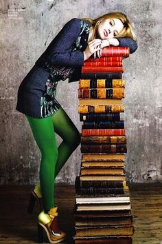 a woman leaning on a stack of books with her hand on her face and wearing green tights