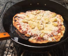 a pizza sitting on top of a grill next to an orange spatula