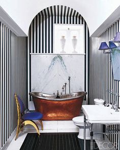 a bathroom with black and white stripes on the walls, an old bathtub in the middle