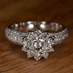 a diamond ring on a wooden table with diamonds around the band and an old - fashioned setting