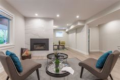 a living room with two chairs and a table in front of a fire place on the wall