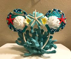 a mickey mouse head made out of seashells and starfish on top of a white table