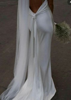 a woman in a white wedding dress holding an umbrella with her back to the camera