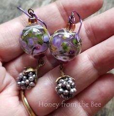 Lavender and green garden lampwork with a blackberry drop - a heavenly pair of artisan earrings One of the sweet treats of nature is coming upon a blackberry bush loaded with sweet juicy berries for the picking.  Ingredients: * lampwork * bronze topped blackberry made from pearls (repurposed/recycled from a high-end pair of clip-on earrings) * glass accents * Niobium earwires These dangle 2.25 inches from the top of the earwire to the bottom of the berry drop. Blackberry Bush, Acorn Necklace, Lampwork Earring, Artisan Earrings, The Bee, Green Garden, Green Earrings, Turquoise Earrings, The Sweet