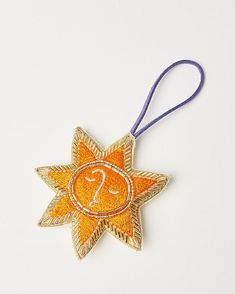 an orange and gold star ornament with the letter s on it's side