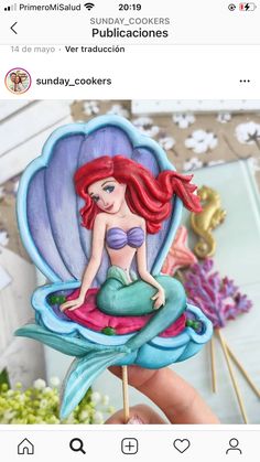 the little mermaid is sitting on top of a blue shell and holding a wand in it's hand