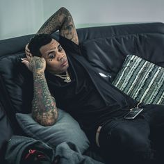 a man with tattoos sitting on a couch