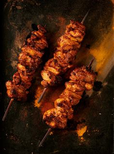 three skewers of meat sitting on top of a grill