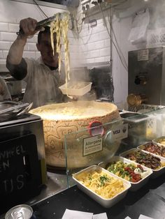 a man cooking food in a kitchen next to other bowls and trays on the counter