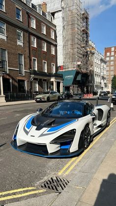 a white and blue sports car parked on the side of a road next to tall buildings