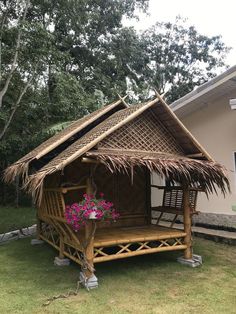 a bamboo hut with flowers in the front yard