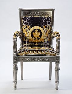 an ornately decorated chair with gold and black designs on the back, sitting against a white background