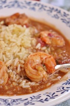 a bowl filled with shrimp and rice on top of a blue and white table cloth