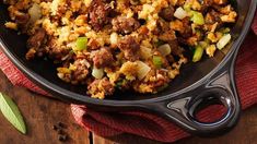 a skillet filled with stuffing on top of a wooden table