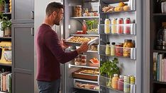 a man is looking into an open refrigerator with food in it and holding the door open